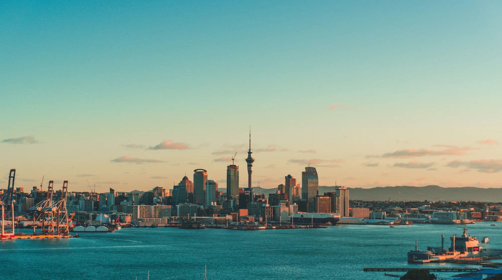 Auckland city skyline at golden hour across the Waitemata Harbour